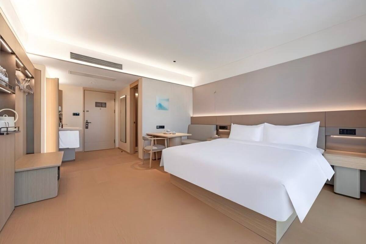 A modern hotel room with a large bed, bedside tables, a desk, and a chair.