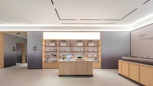 Un interior moderno y minimalista con una isla central, estanterías con diversos objetos y un mostrador de recepción.