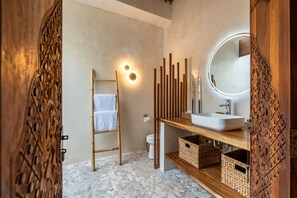 Une salle de bain moderne avec une échelle en bois, un lavabo blanc et un miroir rond avec un éclairage intégré.