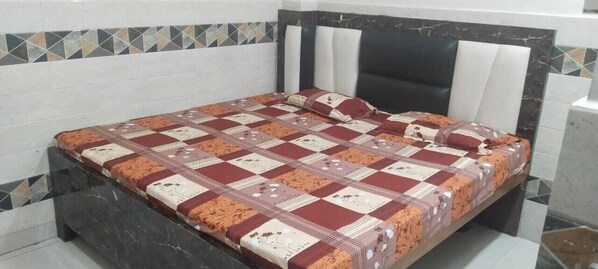 A bed with a patterned bedspread in a room with tiled walls and a marble headboard. - Hotel B K Stay (Mainpuri)