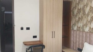 Una stanza con un armadio in legno, un tavolino, una sedia e una parete decorata.