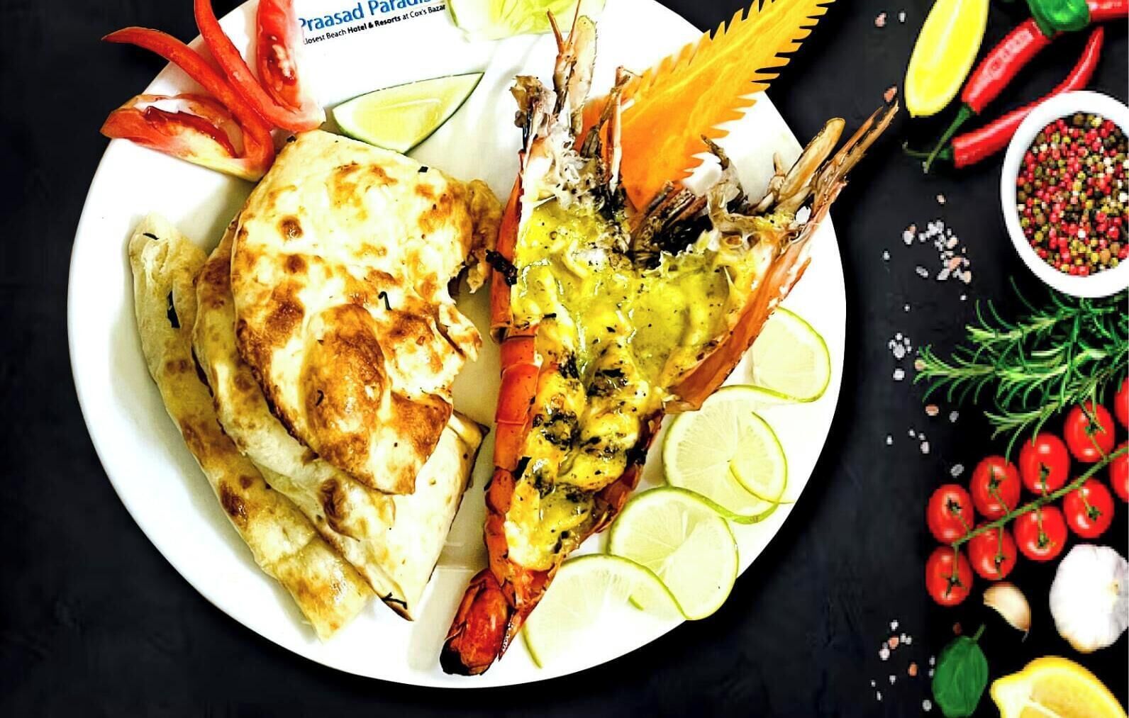 A plate with grilled lobster tail, flatbread, and lime slices.