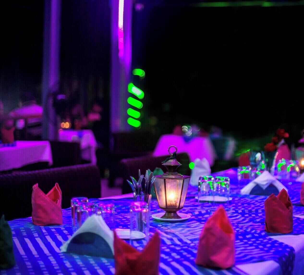 Une table dressée pour le dîner, avec une nappe à motifs, des chandeliers et une lanterne allumée.