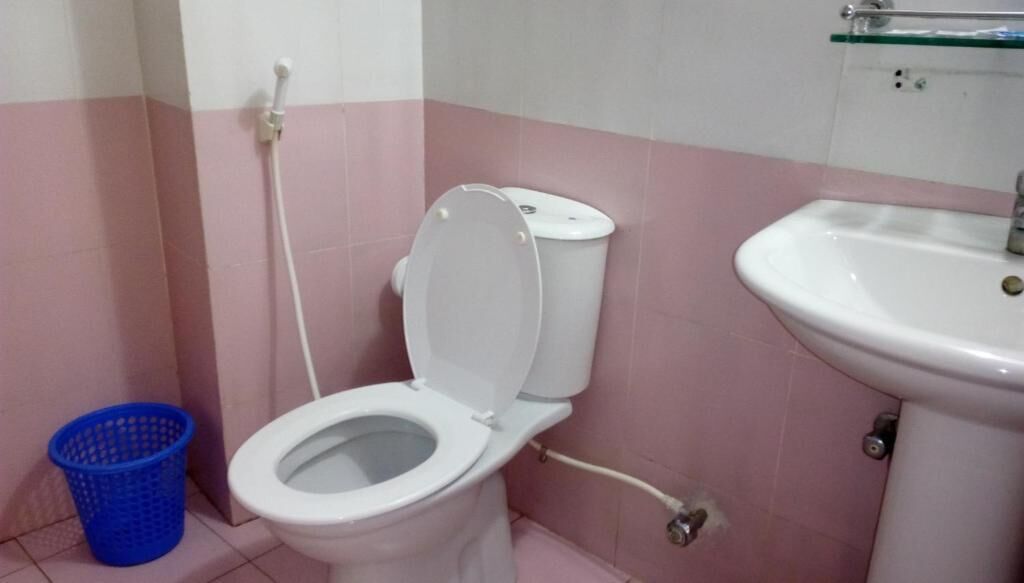 Un baño con inodoro, lavamanos y un cubo de basura azul.
