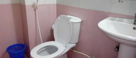 Un baño con inodoro, lavamanos y un cubo de basura azul.