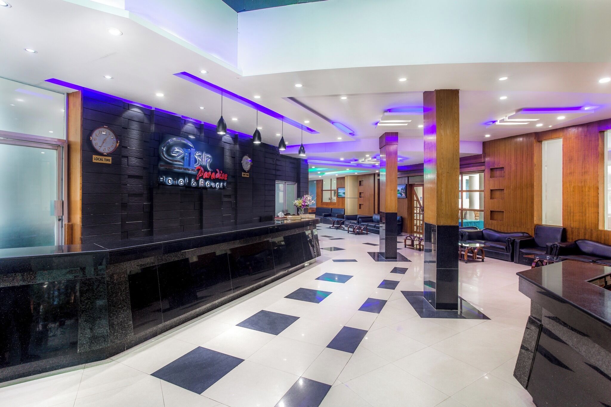 A hotel lobby with a reception desk, seating area, and a clock on the wall.