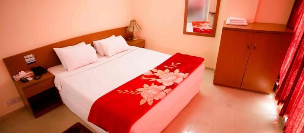 Una habitación de hotel con cama, mesita de noche, armario y espejo.