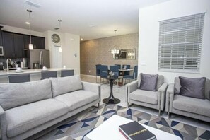 A modern living room with a sofa, armchairs, a coffee table, and a dining area with chairs and a table. - Storey Lake 4 Bedroom Vacation Home 4844 (Kissimmee)