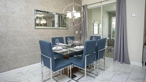 Un comedor con una mesa de vidrio, sillas azules y una lámpara moderna.