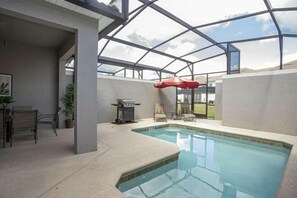 An indoor swimming pool with a glass ceiling, a barbecue grill, and lounge chairs. - Storey Lake 4 Bedroom Vacation Home 4844 (Kissimmee)
