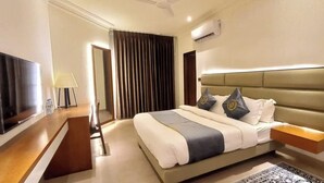 A hotel room with a large bed, a TV, a desk, and a chair. - Royal Pearl Apartment&Suites Cox's Bazar (Cox's Bazar)