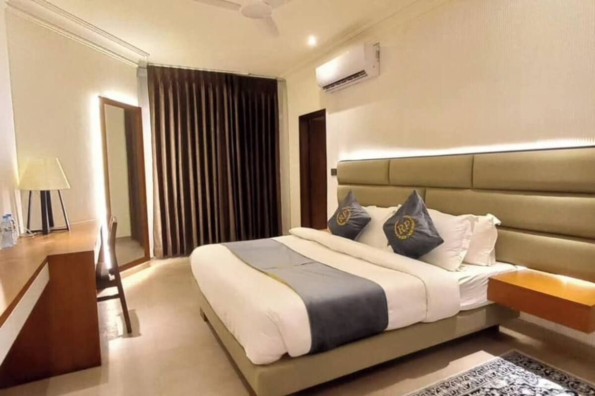 Ein Hotelzimmer mit einem großen Bett, einem Fernseher, einem Schreibtisch und einem Sessel.