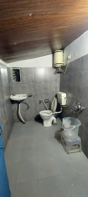 Un baño pequeño con lavamanos, inodoro y calentador de agua instalado en la pared.