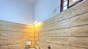 Un baño pequeño con paredes de madera, un inodoro, un lavamanos y una ventana con diseño circular.