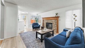 Una sala de estar con chimenea, un sofá, una mesa de centro y un sillón azul.