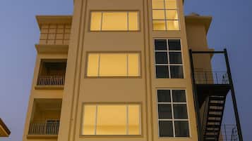 A multi-story building with a flat facade, large windows, and a fire escape on the right side.