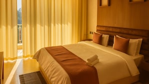 A hotel room with a large bed, a wooden headboard, and a window with curtains. - Xenious Opulent Hamirpur (Barsar)