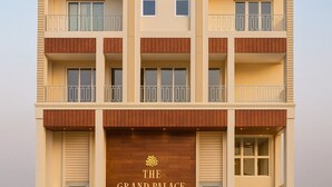 A multi-story hotel with a prominent entrance labeled "The Grand Palace." - Xenious Opulent Hamirpur (Barsar)