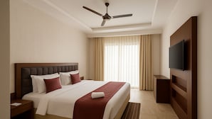 A hotel room with a large bed, a ceiling fan, a TV mounted on the wall, and a window with curtains. - Xenious Opulent Hamirpur (Barsar)
