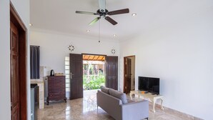 A spacious living area with a ceiling fan, a television, and a sofa. - Awatara Villas and Resort Ubud (Kemenuh)