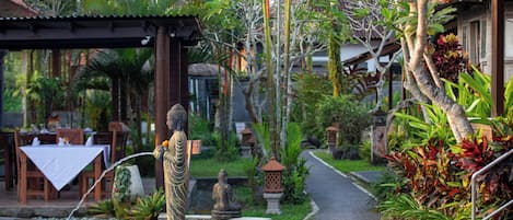Un jardín tranquilo con una estatua, una piscina y un sendero.