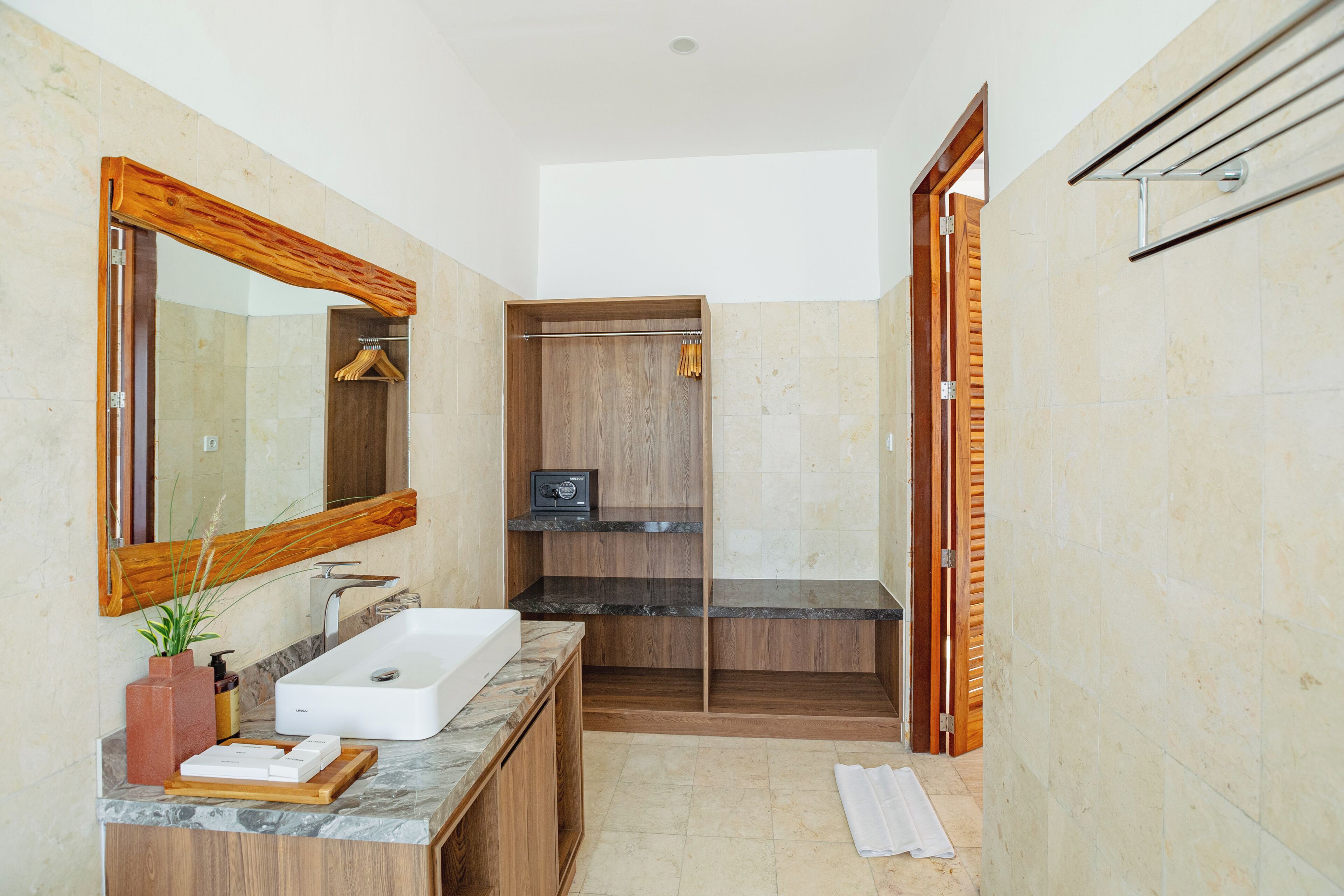 A modern bathroom with a large mirror, a wooden vanity, a built-in shower, and a towel rack.