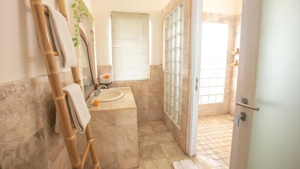 A bathroom with a sink, mirror, and shower area. - Awatara Villas and Resort Ubud (Kemenuh)