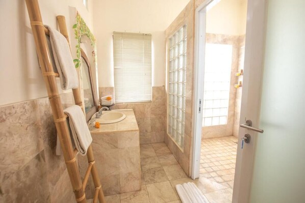 A bathroom with a sink, mirror, and shower area. - Awatara Villas and Resort Ubud (Kemenuh)