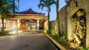 A building with a traditional tiled roof, a reception area with a counter, and a stone wall with a relief sculpture. - Awatara Villas and Resort Ubud (Kemenuh)