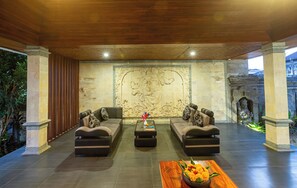 A spacious lounge area with a large carved wall, two sofas, a coffee table, and a decorative vase. - Awatara Villas and Resort Ubud (Kemenuh)