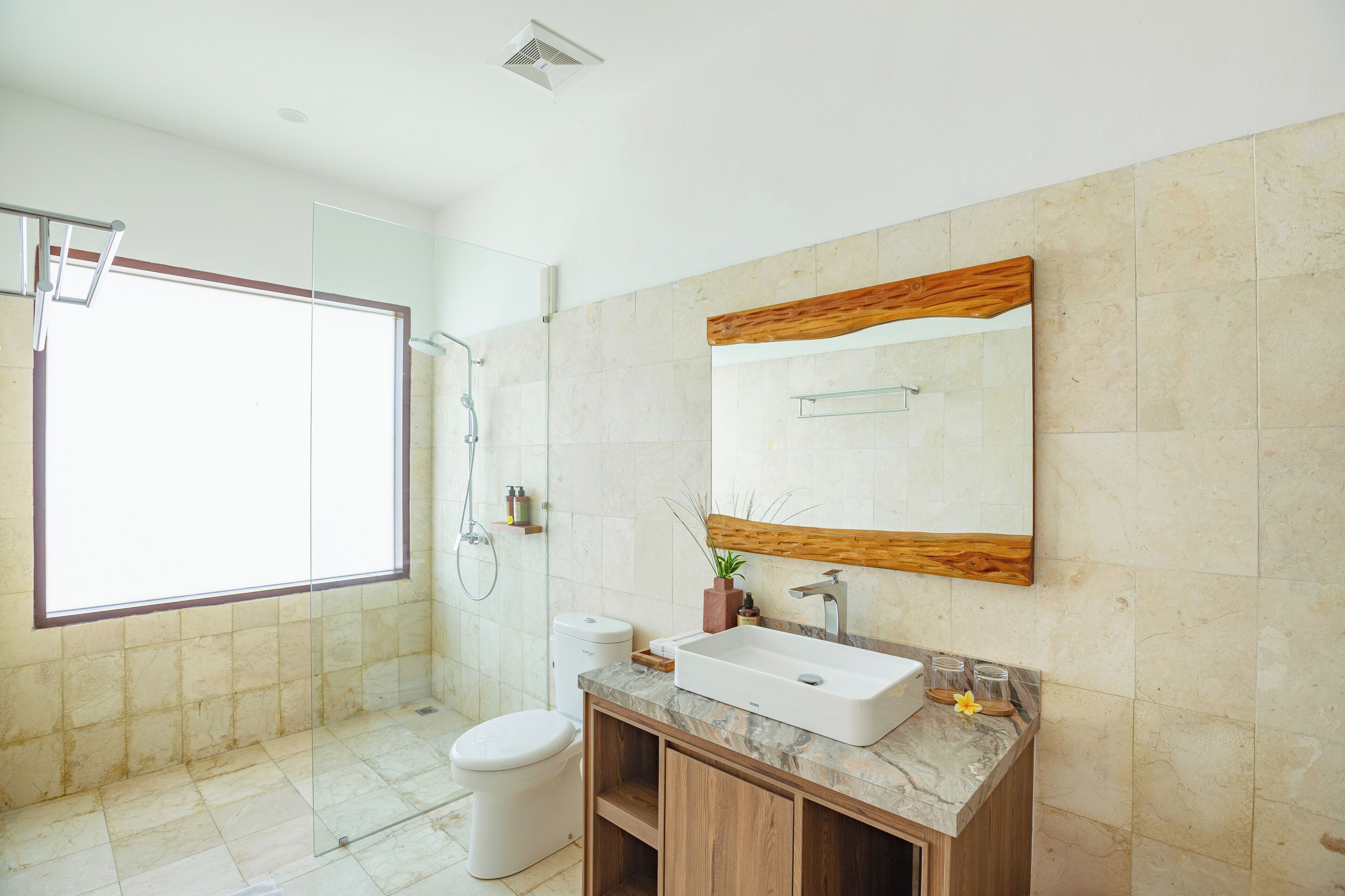 A modern bathroom with a large mirror, a toilet, a shower, and a sink.