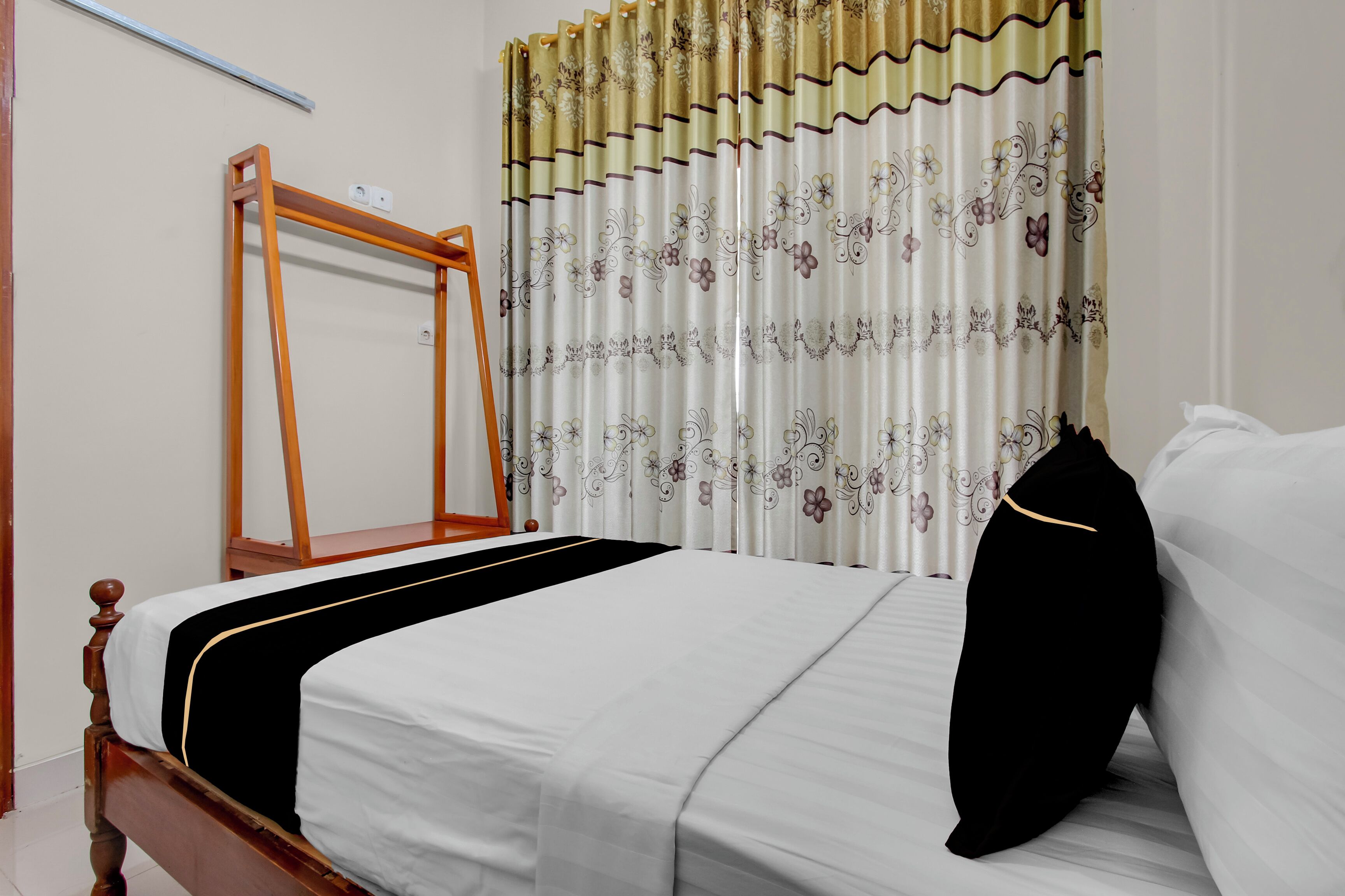 A neatly made bed with a black and white bedspread, a wooden headboard, and a black pillow.
