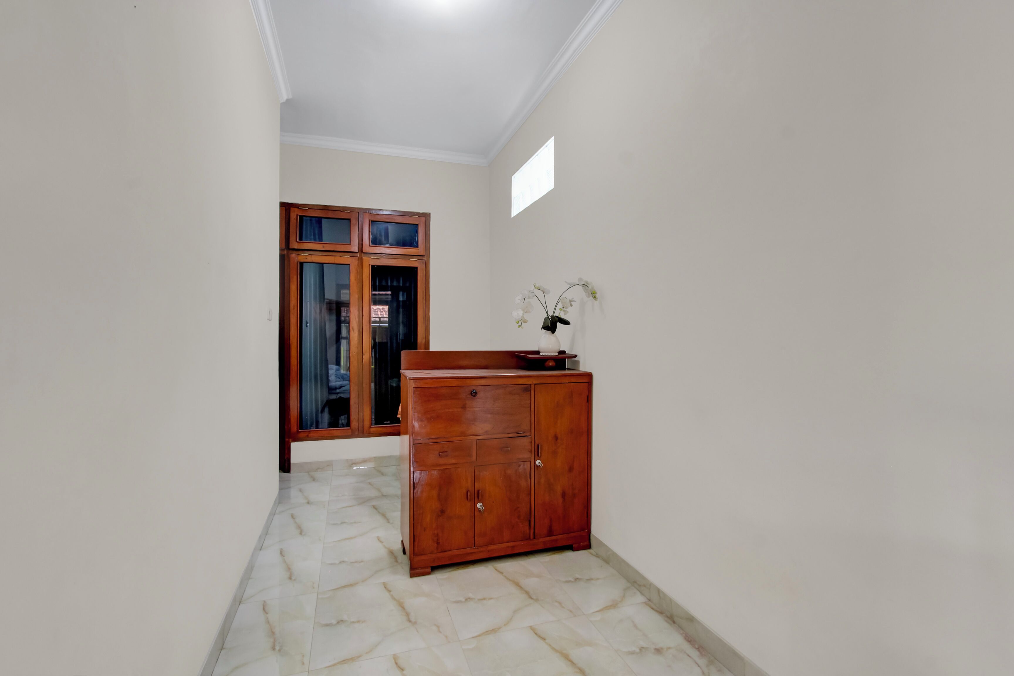 Un pasillo con un armario de madera y una puerta con paneles de vidrio.