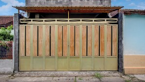 A gated entrance with a metal gate and a concrete wall. - OYO 94920 House Of Elea Minggiran (Yogyakarta)