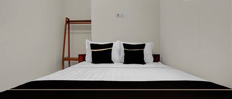 A neatly made bed with white and black bedding, a wooden ladder against the wall, and a small window providing natural light.
