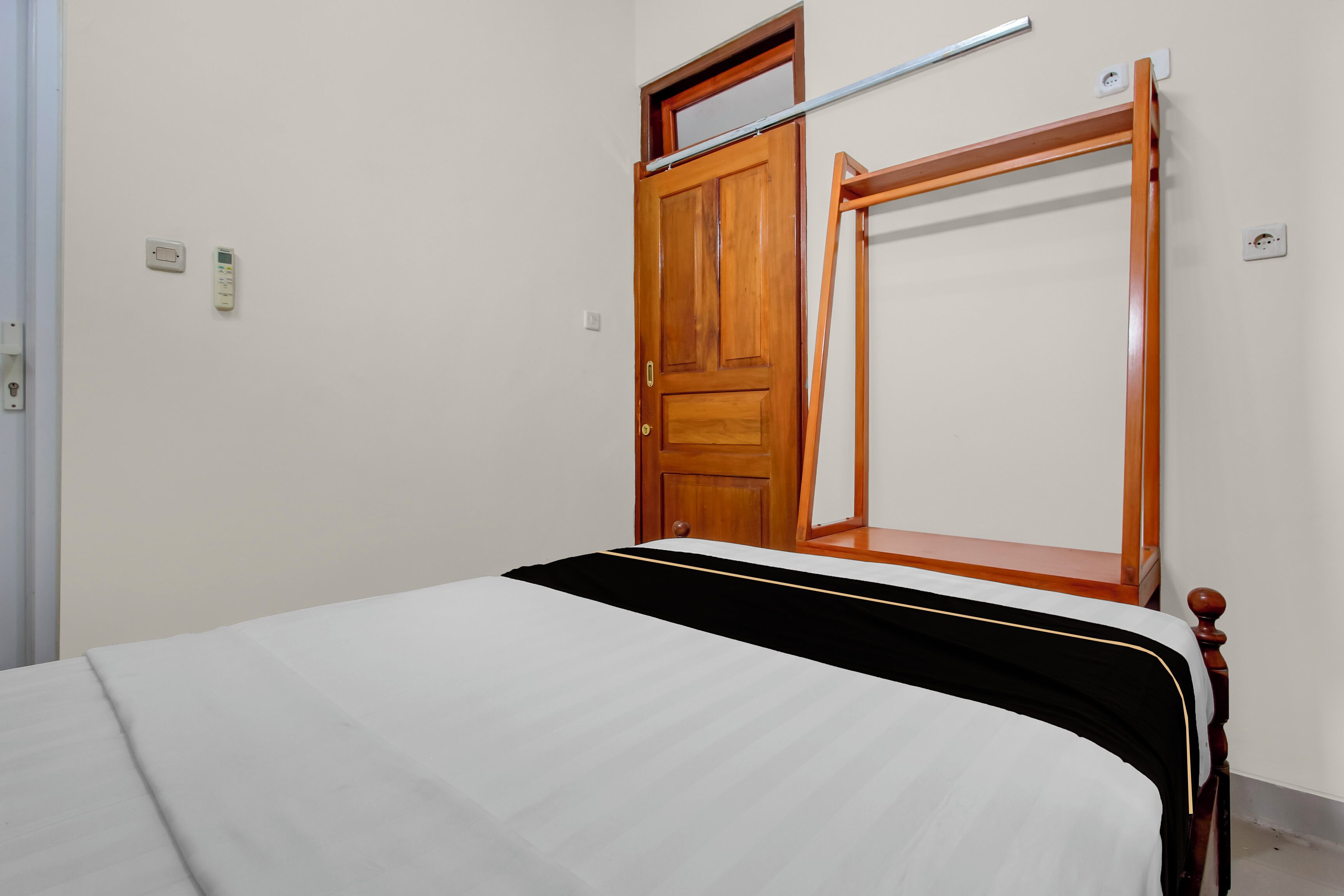 A bedroom with a bed, a wooden wardrobe, and a window.