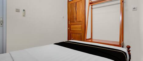 A bedroom with a bed, a wooden wardrobe, and a window.
