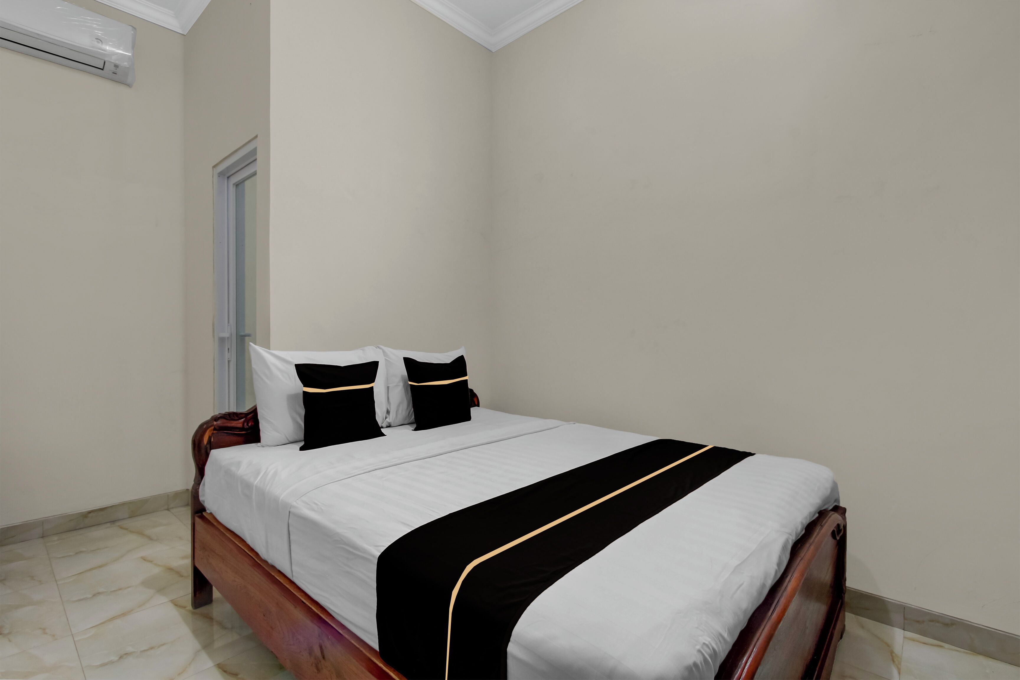 A neatly made bed with a white and black bedspread, a wooden headboard, and two pillows.