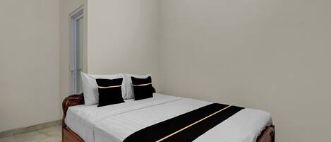 A neatly made bed with a white and black bedspread, a wooden headboard, and two pillows.