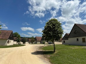 A row of traditional buildings with a dirt path leading through. - Beautiful house in a holiday park with a pool (Lacapelle Marival)