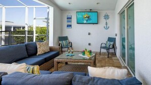 A sunlit patio with a sofa, chairs, a coffee table, and a TV. - Villa Rosa (Cape Coral)