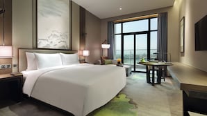 A modern hotel room with a large bed, a desk, a view of the city, and a large artwork on the wall. - LEBANSHAN HOTELS HEFEI (Hefei)