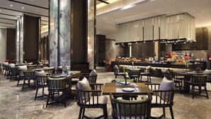 A modern restaurant with multiple dining tables and chairs, a large pillar, and a kitchen area in the background. - LEBANSHAN HOTELS HEFEI (Hefei)