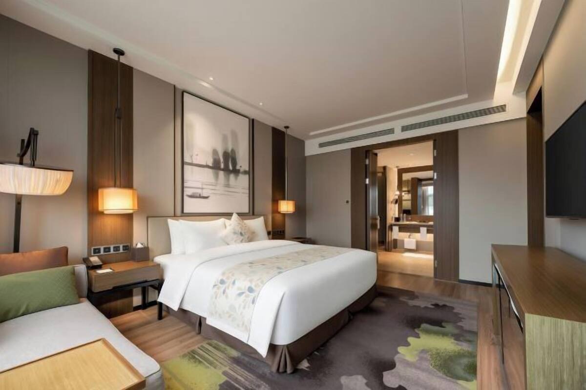 A hotel room with a large bed, bedside lamps, a desk, and a television.