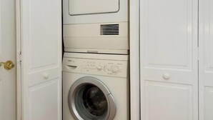 Ein kleiner, weißer Hauswirtschaftsraum mit einer Waschmaschine mit Frontlader und einem Trockner.