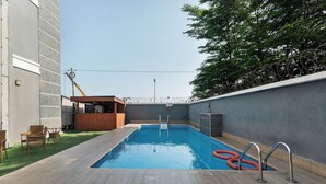 Una piscina rectangular con cubierta de madera, rodeada por un muro bajo y una zona de bar con mostrador de madera.