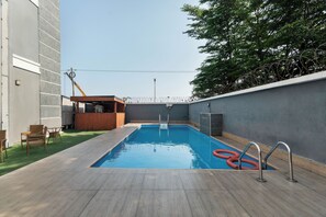 A rectangular swimming pool with a wooden deck, surrounded by a low wall and a bar area with a wooden counter. - 3bed in Lekki Phase 1 - 24/7 Power, Pool, Mini-Gym (Lagos)