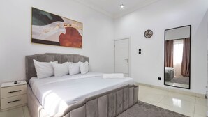 Un dormitorio con una cama grande, una mesita de noche, un espejo en la pared y un cuadro.