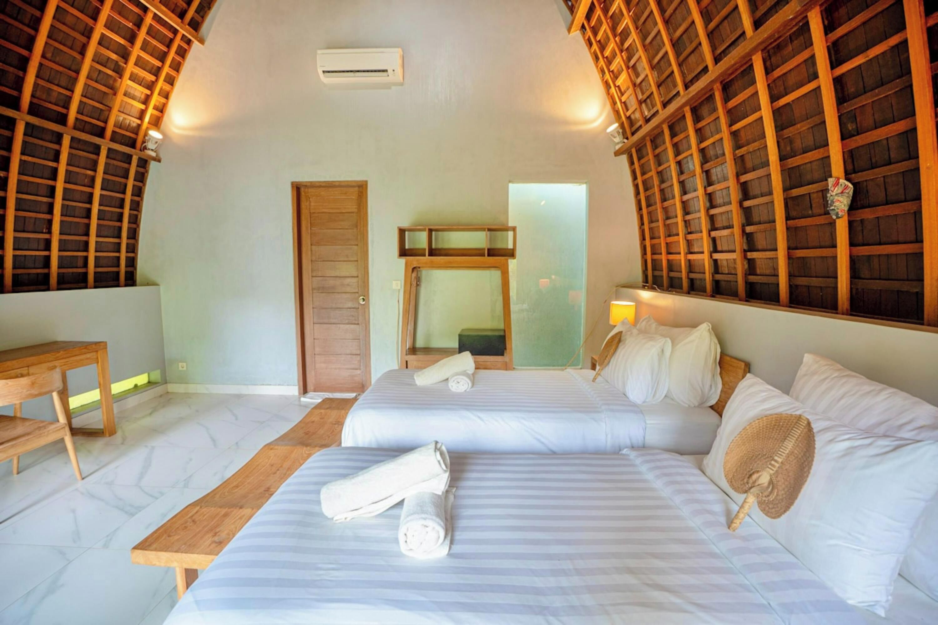 A room with two beds, a wooden desk, and a mirror.