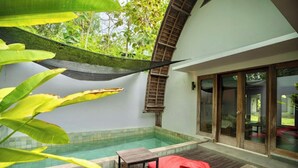 A pool area with a wooden deck, red cushions, and a covered seating area. - Kayu Jati Cottages (Penida Island)